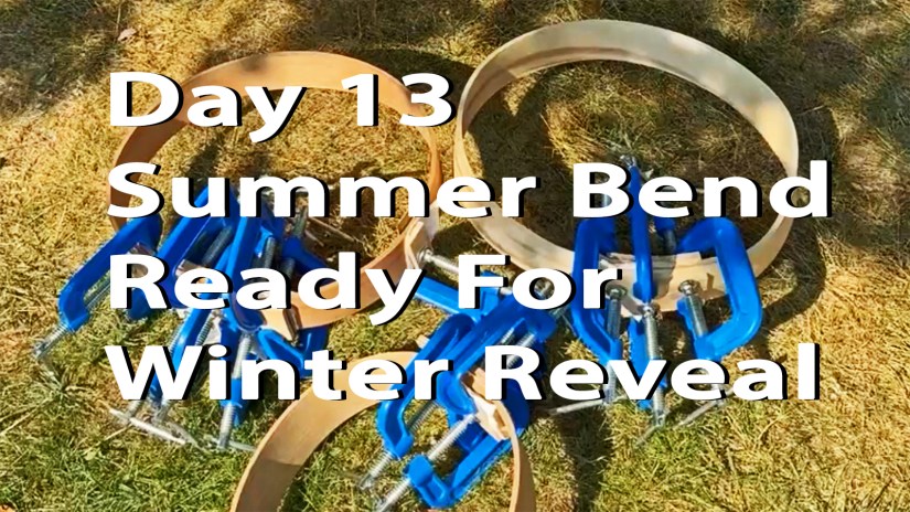Close-up of a wood drum frame with blue C-clamps attached, sitting on grass, from the "Drum December Day 13 Summer Bend Ready For Winter Reveal" blog post by Portia Po Chapman.