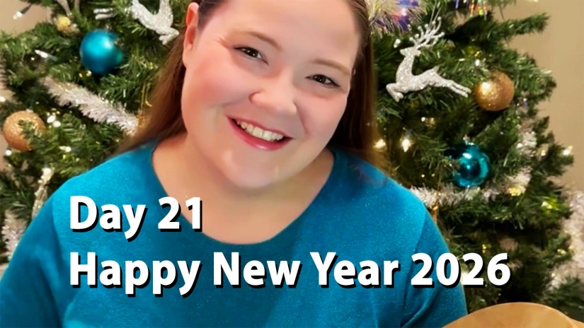 A smiling Portia Po Chapman in a blue shirt standing in front of a decorated Christmas tree. The image includes white text that reads "Day 21 Happy New Year 2026.