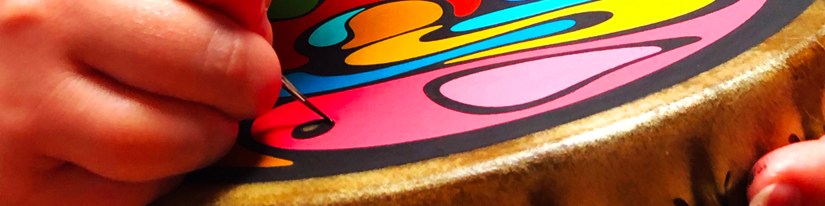 Close-up of Portia "Po" Chapman, Kingston Artist, hand-painting a contemporary rawhide frame drum with vibrant, nature-focused colour-blocking techniques.