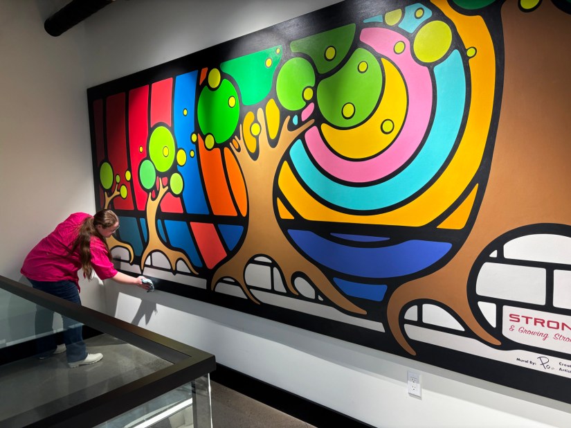 Professional Kingston Artist Portia "Po" Chapman hand-buffing the "Strong and Growing Stronger" mural with a microfibre cloth to ensure a perfect finish.