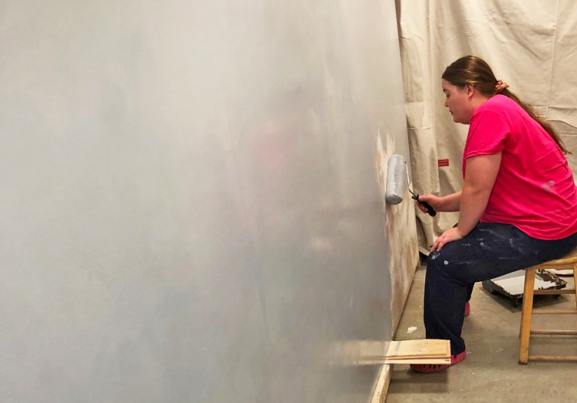 Artist Portia Chapman applying the first of three coats of high-end primer to a large 14-foot mural board in her Kingston studio workshop.