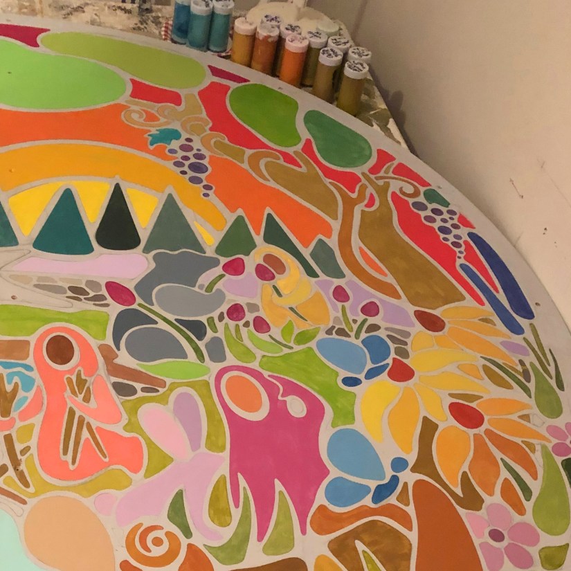 Kingston artist Portia "Po" Chapman applying thin layers of hand-mixed paint to the "Exploring the Senses" mural, prioritizing colour blocks before the black line work.