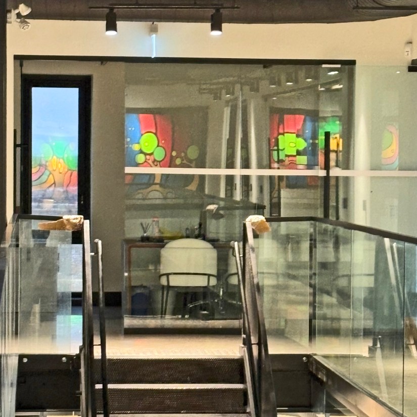 A view from the second-floor mezzanine showing crisp, hand-painted Storytelling Art reflecting in distant glass partitions with vibrant clarity.