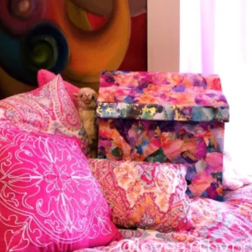 Handmade floral papercraft gift chest by Kingston Artist Portia Po Chapman, styled with vibrant pink pillows and an award-winning oil on canvas swirl painting in the background.