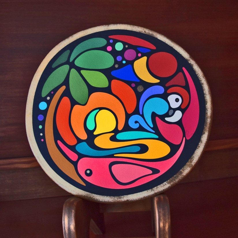 A custom-made Storytelling Art frame drum by Kingston Artist Portia “Po” Chapman, featuring a vibrant Brazilian narrative with a hand-stained red oak frame and custom-mixed paint on rawhide.