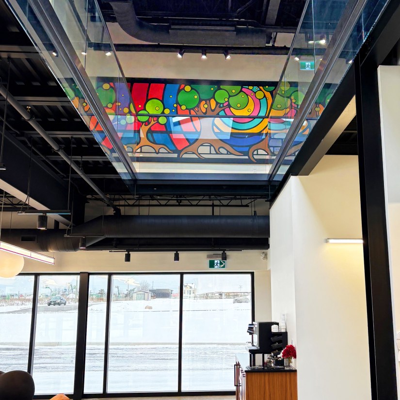 Completed interior mural by Portia Chapman at Strong Enterprises Headquarters, Belleville, viewed from the first floor through a glass mezzanine during winter.