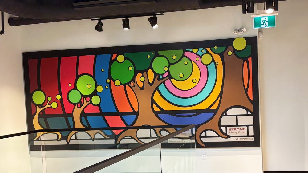 Completed large-scale interior mural by Portia Chapman at Strong Enterprises Headquarters, Belleville. Features freehand brush-painted nature motifs and vibrant geometric patterns on the second-floor mezzanine.