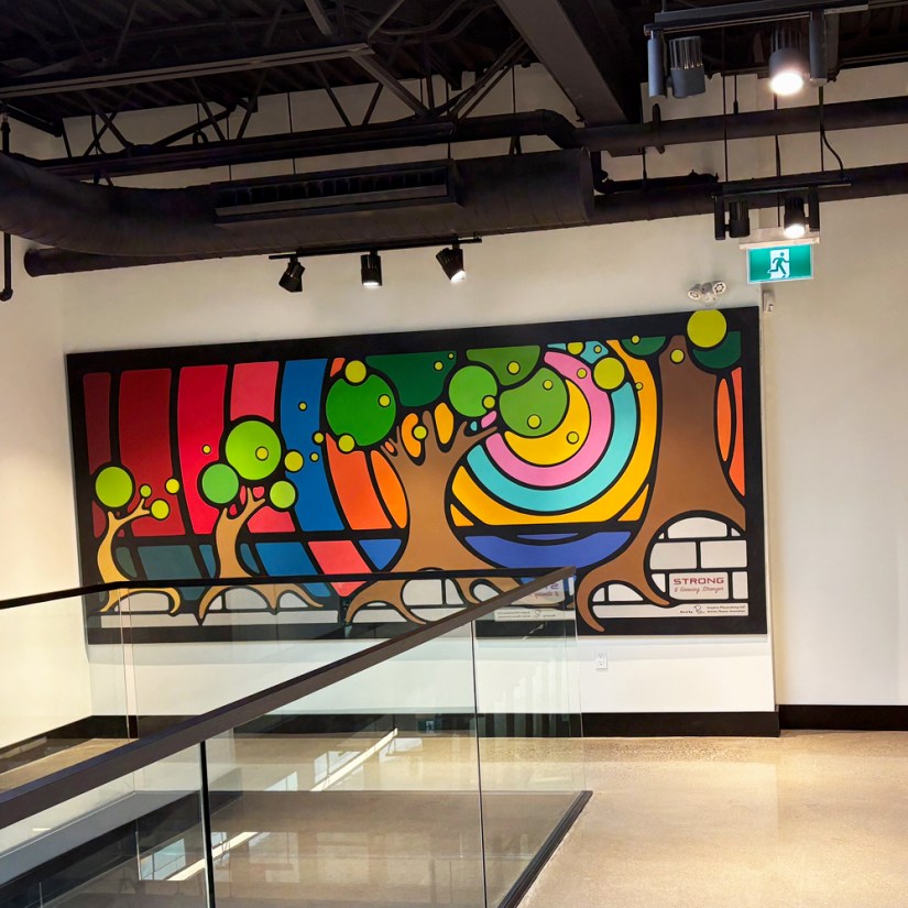 Completed large-scale interior mural by Portia Chapman at Strong Enterprises Headquarters, Belleville. Features freehand brush-painted nature motifs and vibrant geometric patterns on the second-floor mezzanine.