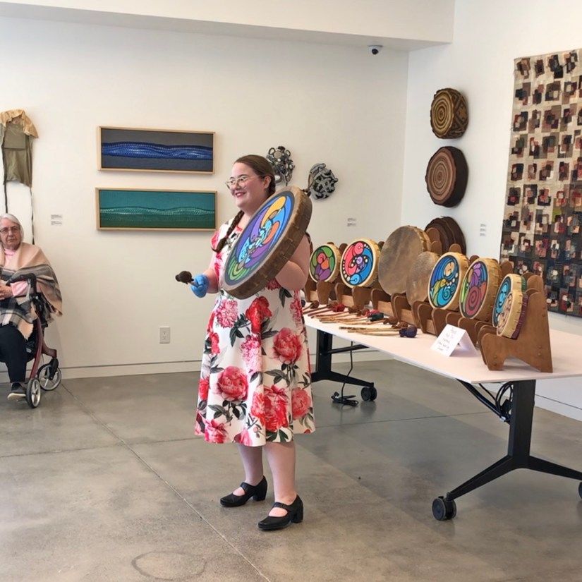 Kingston multidisciplinary artist Portia “Po” Chapman giving an art talk titled "Rawhide, My Preferred Natural Canvas" at the Textile Sampler exhibition in Picton, surrounded by her handcrafted and painted rawhide frame drums.