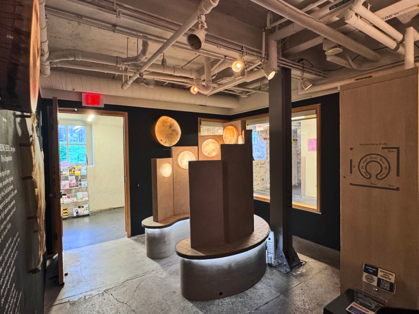 Immersive site-specific installation "Being Seen: when Being Seen... we glow" featuring the monochromatic Glow Chamber, glowing rawhide vessels, vinyl wall text, and photo board inside the Kingston Arts Council Pocket Gallery.